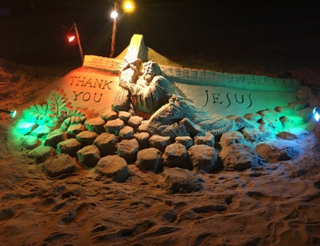 sand sculpture of jesus on the beach with lights